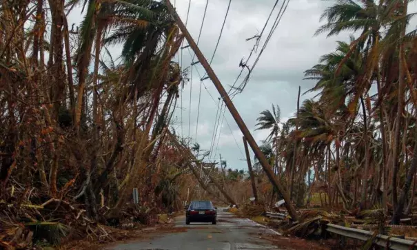 A car drives under tilted power line poles in the aftermath of Hurricane Maria in Humacao, Puerto Rico, Oct. 2, 2017. Photo: Ricardo Arduengo, AFP/Getty Images