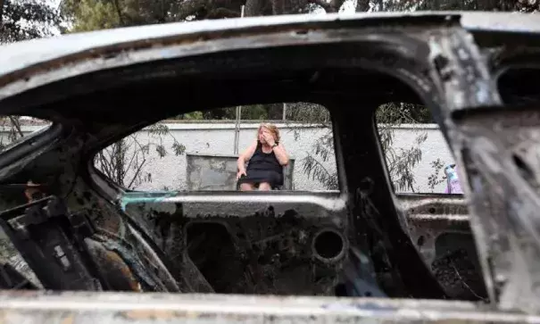 Asimina Psalti, 87, sits outside the remains of her burned house in Mati, Greece, on Tuesday, July 24. Photo: Thanassis Stavrakis, AP