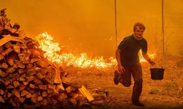 Fifteen year-old Alex Schenck carries a water bucket while fighting to save his home as the Ranch Fire tears down New Long Valley Rd near Clearlake Oaks, California, on Saturday, August 4, 2018. Noah Berger, AFP/Getty Images