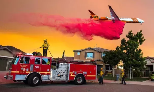A plane drops fire retardant behind homes along McVicker Canyon Park Road in Lake Elsinore, California, as the Holy Fire burns near homes on Wednesday, Aug. 8, 2018. Photo: Weather Underground
