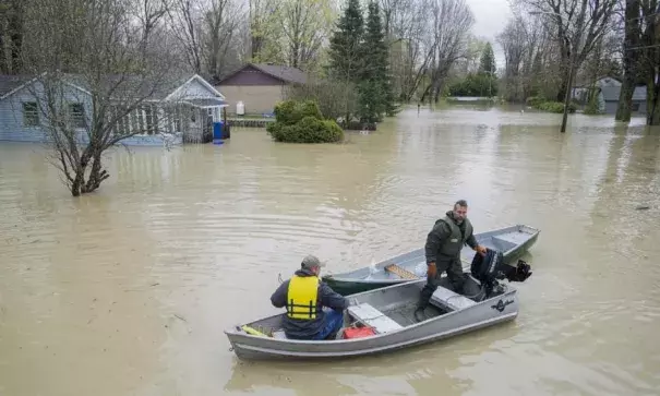 Two men move along a flooded street using a small boat in the town of Rigaud, west of Montreal, Sunday, following flooding in the region. In total, nearly 1,900 homes are flooded in 126 municipalities in Quebec. Photo: Graham Hughes, The Canadian Press