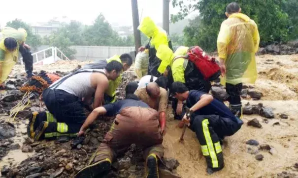 Firefighters dig out a family of seven that were caught in a landslide in New Taipei City’s Wulai District yesterday during the onslaught of Typhoon Soudelor. All seven survived the ordeal. Photo: CNA