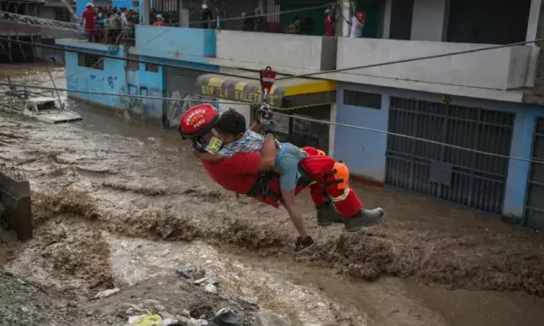 A policeman rescues a boy who was among people trapped in buildings by flash flooding in Lima, Peru. The El Niño climate phenomenon is causing muddy rivers to overflow along the Peruvian coast, isolating communities. Photo: AFP
