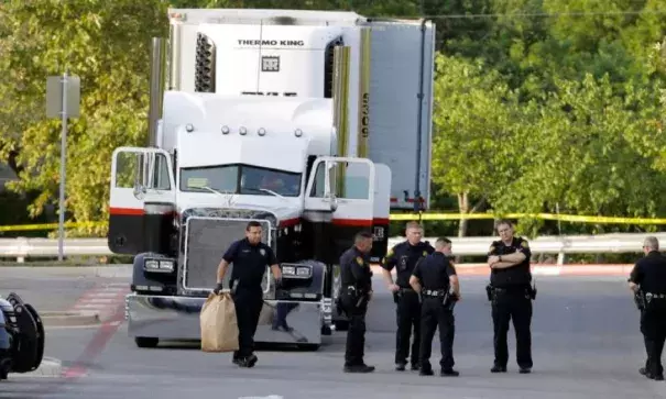 San Antonio police officers investigate the scene where eight people were found dead in a tractor-trailer loaded with at least 30 others outside a Walmart store. Photo: The Associated Press