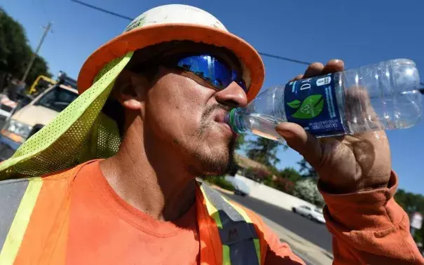 Miguel Lunar of Madco Electric takes a swig of cold water during work at Palm and Shields avenues to install traffic sensors under the roadway surface on June 21. Photo: John Walker, Fresno Bee