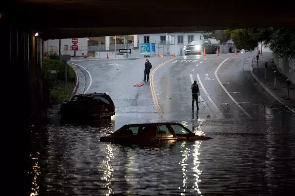 People photograph a car sitting in flooded water at an underpass on Jan. 4, in Oakland, Calif. (Credit: Marlena Sloss for The Washington Post)