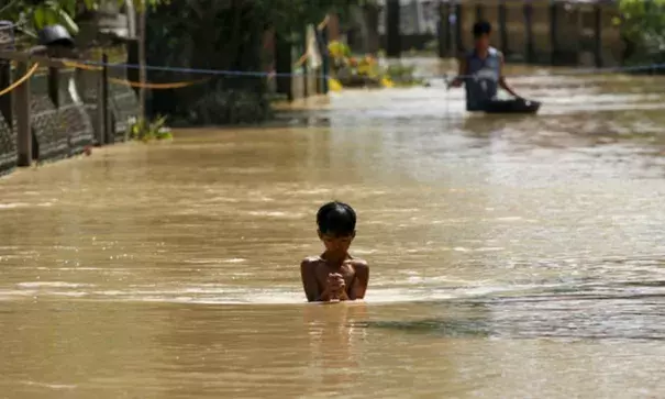 A boy wades through a flooded street in Jaen, Nueva Ecija, in northern Philippines: the death toll from Typhoon Koppu has now risen to 54. Photograph: Erik de Castro/Reuters