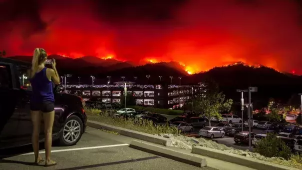 A woman takes photos from the upper parking lot of the Cache Creek Casino Resort overlooking the County fire as it burns out of control Saturday in Brooks, Calif. The blaze spread quickly overnight. Credit: Peter DaSilva, EPA, Shutterstock