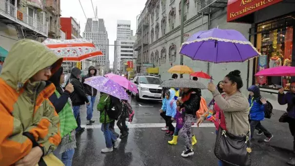 Pedestrians take cover in the Chinatown district of San Francisco as a powerful storm rolled into the Bay Area. Image: Ben Margot / Associated Press)
