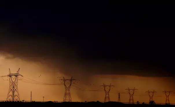 Rain falls behind power lines near Adelanto at the end of a scorching hot day. Photo: Luis Sinco / Los Angeles Times