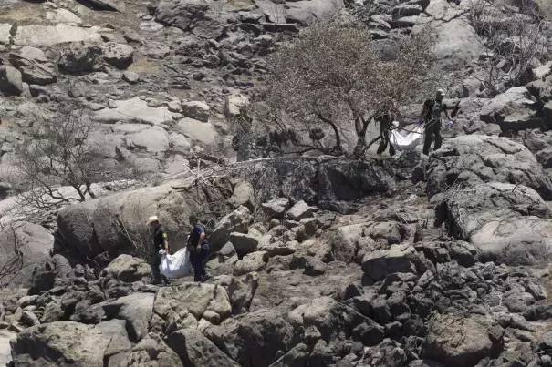 Deputies carry the remains of two victims of the Border fire down from the hillside where their bodies were discovered by neighbors. Photo: John Gibbins / San Diego Union-Tribune