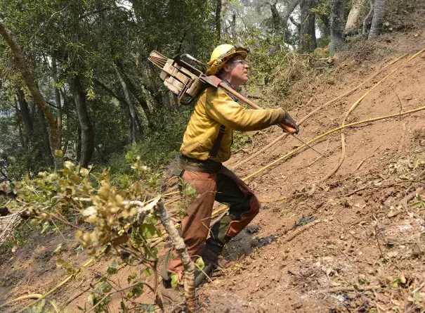 Jeff Turpin hikes up a hillside with his chain saw Saturday while cutting a fire break for the Soberanes fire. Photo: David Royal / Monterey County Herald via AP