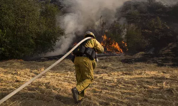 A firefighter rushes to battle flames as brush fires broke out in the Calabasas and West Hills areas. Photo: Brian Vander Brug, Los Angeles Times)