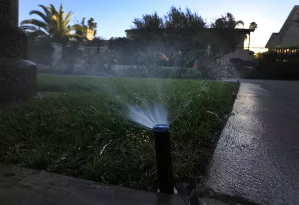 Sprinklers water a lawn at dusk in Beverly Hills. Statewide, Californians cut their urban water use in March by 24.3% compared with the same month in 2013, regulators said. Photo: LA Times