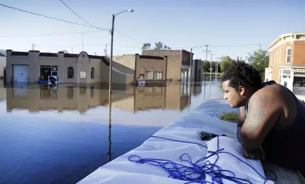 Cory Harrison stands on a flood wall as he looks over businesses flooded by the Cedar River on Sept. 27 in Cedar Rapids, Iowa. Photo: Charlie Neibergall, Associated Press)