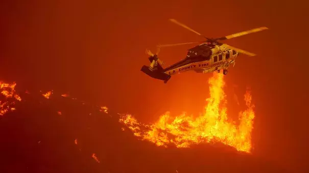 A firefighting helicopter hovers close to the flames from the Sand fire as it burns out of control along Soledad Canyon Road. Photo: Luis Sinco / Los Angeles Times