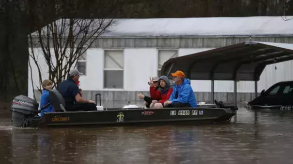 Sarah Yatcko, left, holds her son Tucker Neal as they are evacuated by boat with her father Jim Yatcko, by Bossier County Sheriff personnel during rising floodwaters in Bossier Parish, La., Thursday, March 10, 2016. Photo: AP, Gerald Herbert