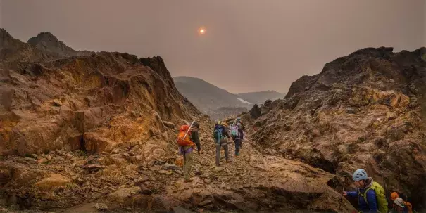 Haze from wildfire smoke obscures the sun as U of A researcher Zac Robinson leads students on a hike in B.C.'s Monashee Mountains in August 2018. Robinson is one of the editors of a new report focusing on how wildfires are affecting Canada's alpine regions. Photo: Mary Sanseverino