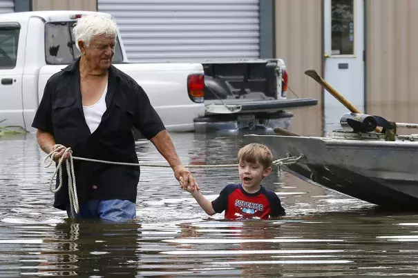 Richard Rossi and his four-year-old great-grandson, Justice, wade through water in search of higher ground after their home flooded in St. Amant, Louisiana. Photo: Jonathan Bachman / Reuters
