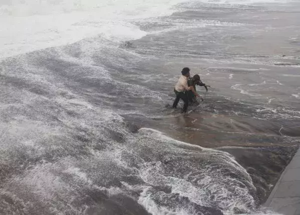 A man carries his wife to a safer ground after a wave hits a beach in Gopalpur in Ganjam district in the eastern Indian state of Odisha October 12, 2014. Image: Stringer, Reuters