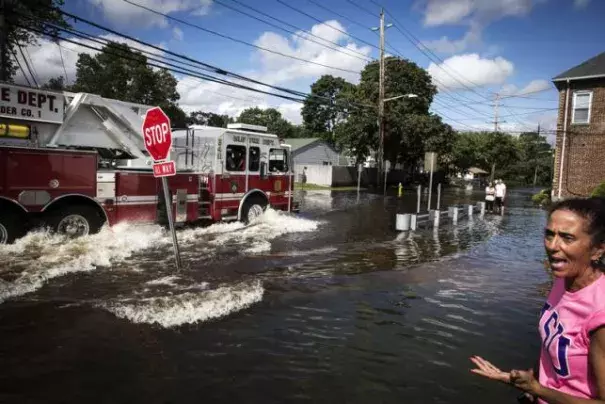 A resident watches as emergency personnel drive their truck through a flooded intersection in Islip, New York August 13, 2014. Photo: Lucas Jackson, Reuters