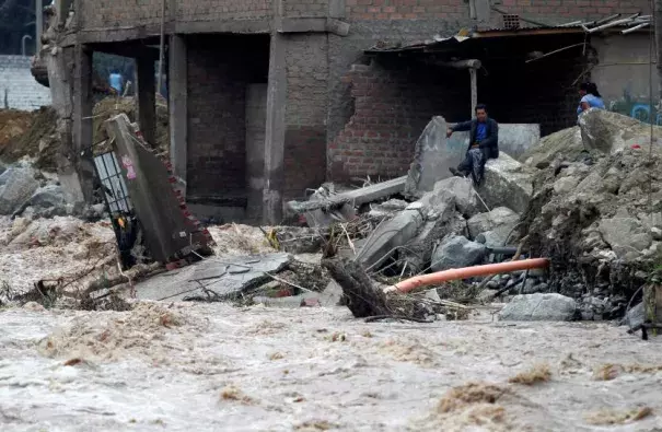 Man sits near a flooded home after the Rimac river overflowed near the Central Highway in Huarochiri, Lima, Peru, March 23, 2017. Photo: Guadalupe Pardo, Reuters