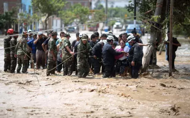 Police help residents cross a flooded street after a massive landslide and flood in the Huachipa district of Lima, Peru, March 17, 2017. Photo: Sebastian Castaneda, Reuters