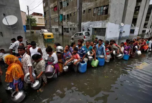 People queue to collect drinking water from a municipal tanker at a flooded residential colony in Ahmedabad, India, July 29, 2017. Photo: Thomson Reuters Foundation