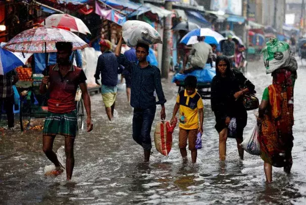 People walk on the water as roads are flooded due to heavy rain in Dhaka, Bangladesh July 26, 2017. Photo: Mohammad Ponir Hossain, Reuters
