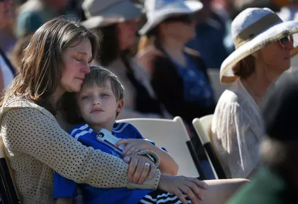 Laura Schulze, above, holds her son Zachary, 8, during the Day of Remembrance at Santa Rosa Junior Col lege, where hundreds of community members, officials and first responders gathered in Bailey Field, below. Photo: Leah Millis, The Chronicle