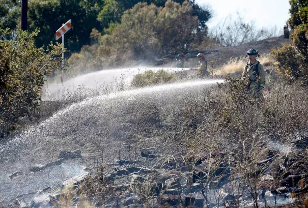Firefighters extinguish hotspots from a four-alarm fire that consumed 24 acres on a dry hillside in Cordelia, Calif. on Friday, June 7, 2019. Photo: Paul Chinn, San Francisco Chronicle
