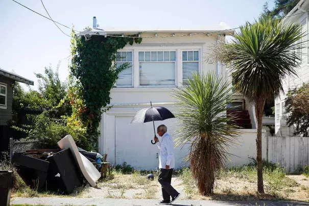 Berhane Woldeabzghi takes cover from the sun as he strolls through his Oakland neighborhood. Photo: Lea Suzuki, The Chronicle