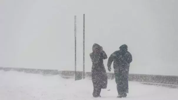 Two people brave high speed winds Tuesday at Revere Beach. Photo: Ryan McBride, AFP, Getty Images