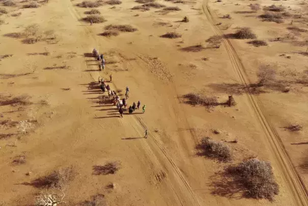 People are shown walking along a dirt path.