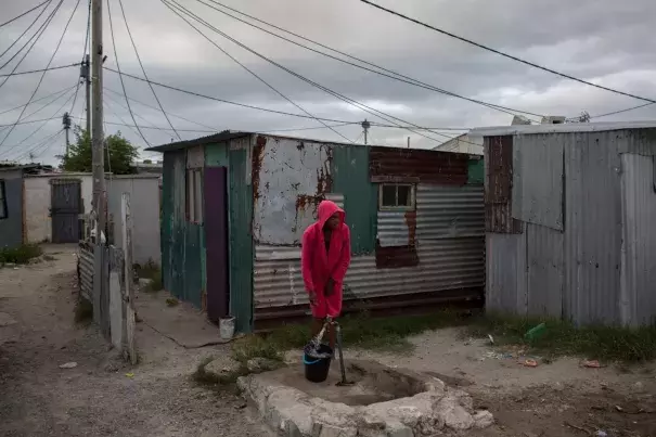In this Feb. 2, 2018 photo, a woman collects water in a settlement near South Africa’s drought-hit city of Cape Town. About a quarter of Cape Town’s population lives in the informal settlements, where they get water from communal taps instead of individual taps at home like in the richer suburbs. And they use 4.5 percent of the total water consumption. Photo: Bram Janssen, AP