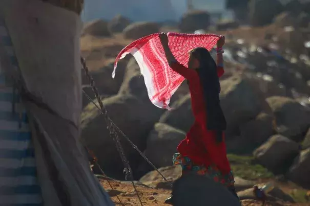 An internally displaced girl carries a scarf as she stands outside tents at a makeshift refugee camp in Sinjar town, in Idlib province, Syria, November 20, 2015. Photo: Ammar Abdullah, Reuters