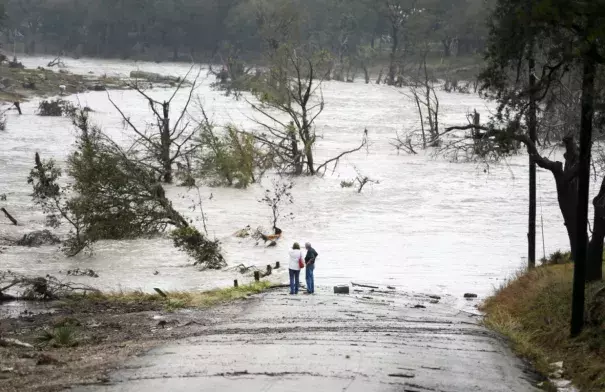 Jim Richardson and his wife, Jeannette, look on as the Blanco River recedes after a flash flood in Wimberly, Tex., on Friday. (Ricardo Brazziell/Austin American-Statesman via AP)