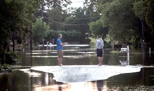 Ben Yock and Dustin Nichols survey the damage done to Nichols’ neighborhood from a dry patch of asphalt in the middle of Bogie Dr. in San Marcos after heavy rains caused more flooding in the areas around the Blanco River on Monday, May 25, 2015. Photo: The Texas Tribune / Flickr