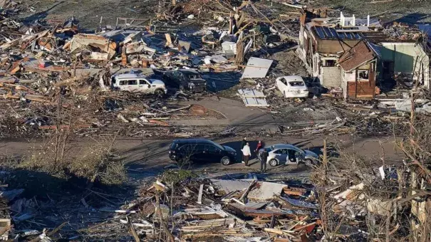 People stand amidst destruction from a recent tornado in downtown Mayfield, Ky., Dec. 12, 2021. (Credit: Gerald Herbert/AP)