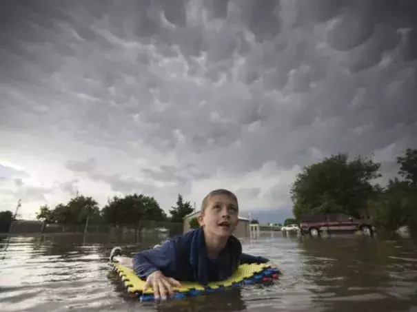 Kevin Weibe floats down his street in Scott City, Kan., while looking up at mammatus clouds after heavy rains inundated the small, western Kansas town on Tuesday, June 19, 2018. High heat will be the main weather story in the central U.S. over the next few days. Credit: Travis Heying, AP