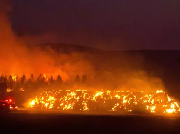 A firetruck moves along Highway 125 past a blazing stack of hay bales north of Walla Walla, Wash., during a large wildfire on Aug. 21, 2016. Photo: Greg Lehman, Walla Walla Union-Bulletin, via AP