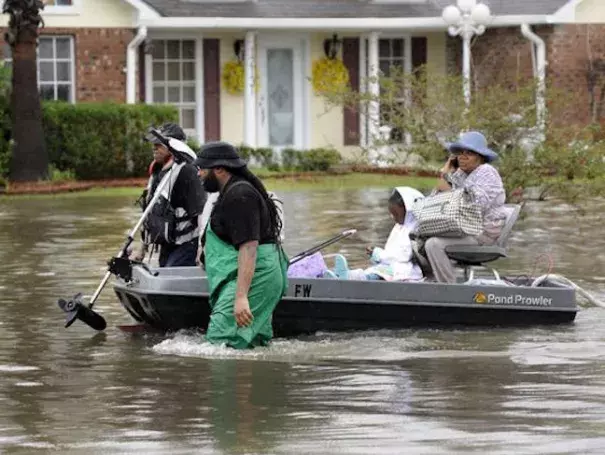 olunteers pull a boat with a woman and young child as they evacuate from their homes on Aug. 13, 2016, in Baton Rouge. Photo: John Oubre/The Advocate via AP