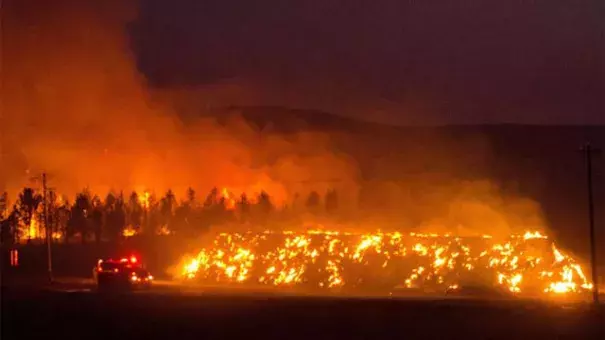 A fire truck moves along Hwy 125 past a blazing stack of hay bales north of Walla Walla during a large wildfire Aug. 21, 2016. The fire, whose cause is under investigation, burned about 15,000 acres. Photo: Greg Lehman / Walla Walla Union-Bulletin via AP