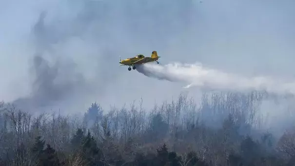 A crop duster drops water on a wildfire north of Hutchinson, Kan., on Tuesday, March, 7, 2017. Wildfires have erupted across the Kansas over the last 24 hours. Photo: Travis Heying, Wichita Eagle via AP