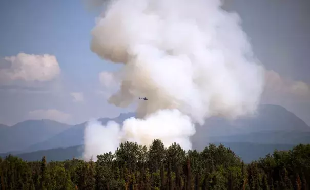 A helicopter passes by as smoke rises from a wildfire on July 3, 2019 south of Talkeetna, Alaska near the George Parks Highway. Credit: Lance King, Getty