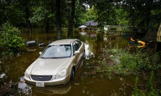 A car and home sit in floodwater from Spring Creek along North Ravenswood Drive on Friday in Magnolia, Texas. Photo: Michael Ciaglo, AP