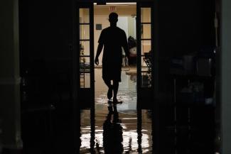 A resident's relative walks through the Peach Tree Village nursing home to collect family possessions from the flooded facility in Brandon, Miss., following a morning of torrential rains, Wednesday, Aug. 24, 2022. Heavy rains and flash flooding prompted rescue operations, closures and evacuations in the central part of the state. (Credit: AP Photo/Rogelio V. Solis)