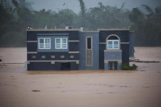 A home is submerged in floodwaters caused by Hurricane Fiona in Cayey, Puerto Rico, Sunday, Sept. 18, 2022. According to authorities three people were inside the home and were reported to have been rescued. (AP Photo/Stephanie Rojas)