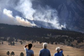 From left, Laura Tyson, Tod Smith and Rebecca Caldwell, residents of Eldorado Springs, watch as the NCAR fire burns in the foothills south of the National Center for Atmospheric Research, Saturday, March 26, 2022, in Boulder, Colo. The NCAR fire prompted evacuations in south Boulder and pre-evacuation warning for Eldorado Springs. (Credit: Helen H. Richardson/The Denver Post via AP, File)