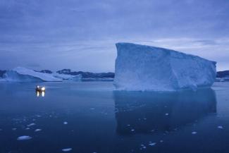 FILE - A boat navigates at night next to large icebergs in eastern Greenland on Aug. 15, 2019. Zombie ice from the massive Greenland ice sheet will eventually raise global sea level by at least 10 inches (27 centimeters) on its own, according to a study released Monday, Aug. 29, 2022. Zombie or doomed ice is still attached to thicker areas of ice, but it’s no longer getting fed by those larger glaciers. (Credit: AP Photo/Felipe Dana, File)